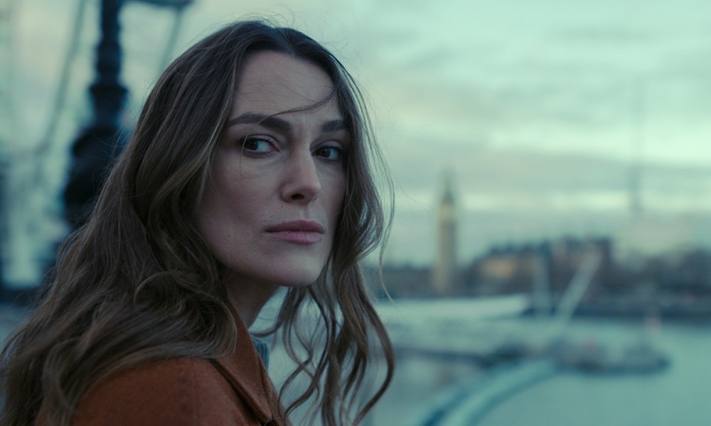 A close-up of Keira Knightley looking back at something on the street in Black Doves.